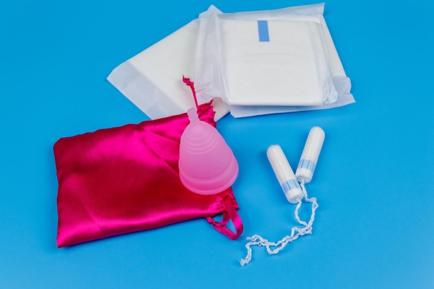 Sanitary pad tampons and menstrual cup on blue background Concept of critical days menstruation feminine hygiene