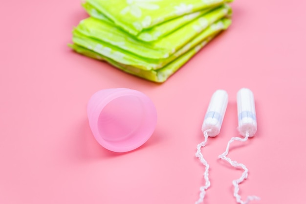 Photo sanitary pad tampons and menstrual cup on pink background concept of critical days menstruation feminine hygiene