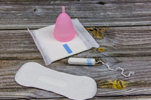 Sanitary pad tampons and menstrual cup on wooden background Concept of critical days menstruation feminine hygiene