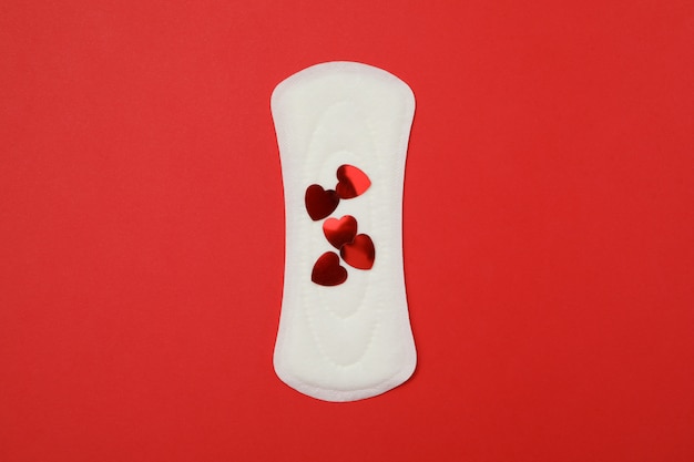 Гигиеническая прокладка с маленькими сердечками на красной поверхности