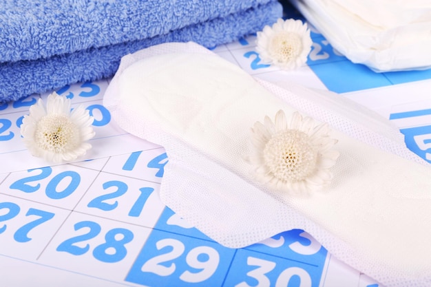 Sanitary pads white flowers and towel on blue calendar background