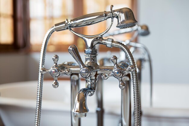 sanitary, plumbing and washing concept - close up of bath tap and shower at bathroom