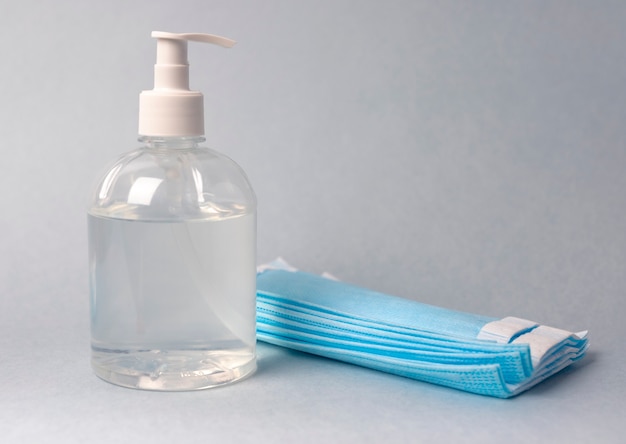 Sanitizer in bottle with surgical masks over blue.