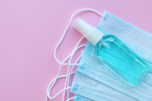 Sanitizer and face masks on a pink table