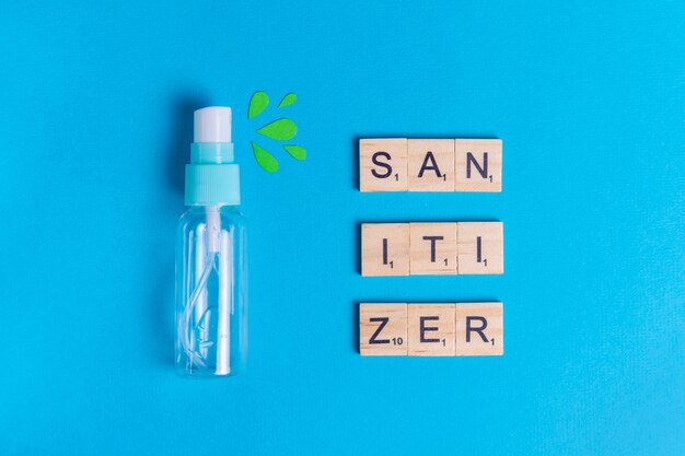 Sanitizer in spray on a blue background with green drops to protect health from bacteria and viruses