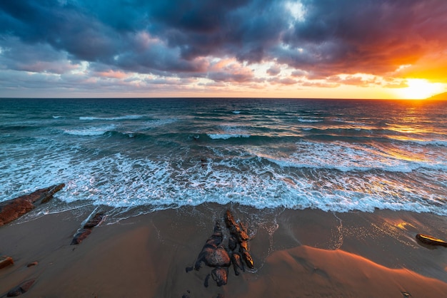 Sanremo Riviera dei Fiori Liguria Italy Scenis rocks and pebbles on beach illuminated beautiful by sunset light Dramatic colourful sky waving sea