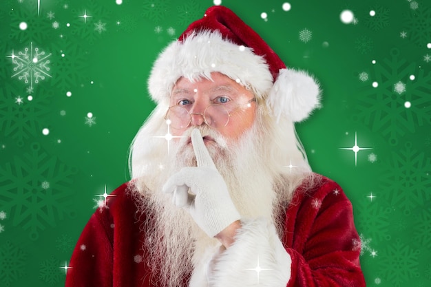 Santa asking for quiet to camera against green snowflake background