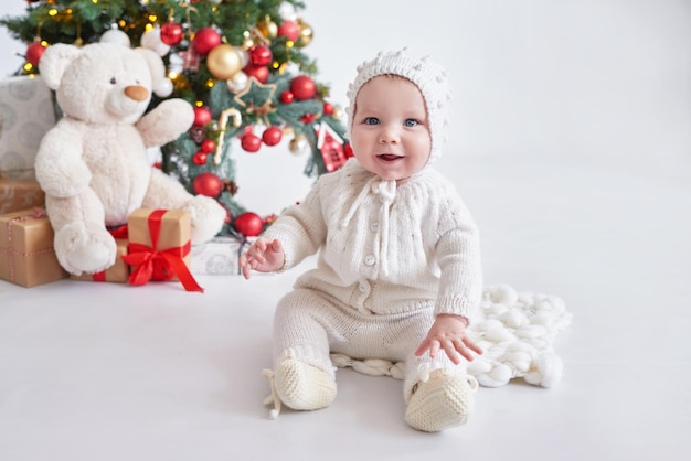 Santa baby Christmas tree background Happy New Year Child in knitted suit