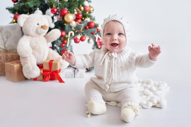 Santa baby Christmas tree background Happy New Year Child in knitted suit