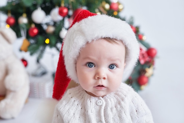 Santa baby Christmas tree background Happy New Year Child in Santa's hat