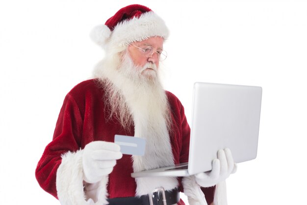 Santa betaalt met een creditcard op een laptop