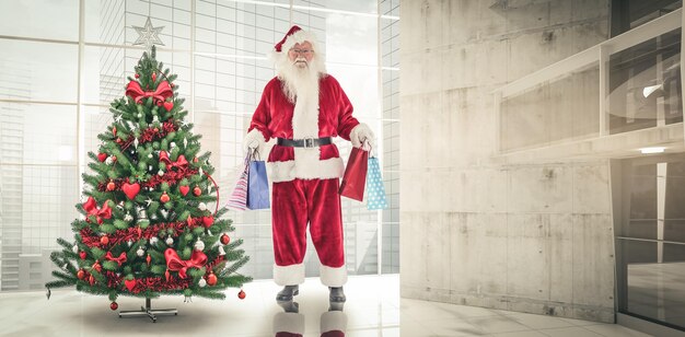 Foto babbo natale porta alcuni sacchetti di natale contro casa con l'albero di natale