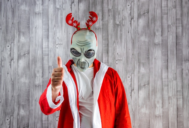 Санта-Клаус в костюме инопланетянина с большими пальцами руки вверх