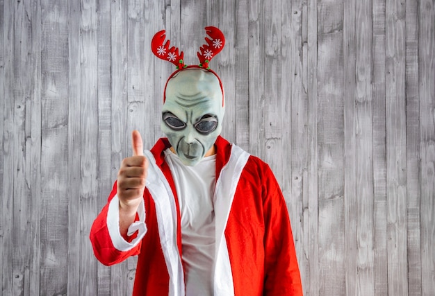 Foto babbo natale in costume da alieno con il pollice in alto