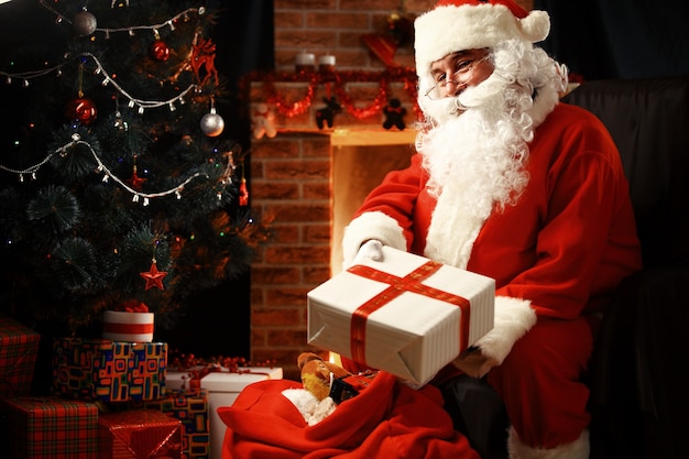 Santa Claus brought gifts for Christmas and having a rest by the fireplace. Home decoration