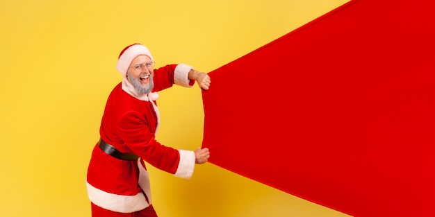 Santa claus carrying big bag with presents, copy space for advertisement.