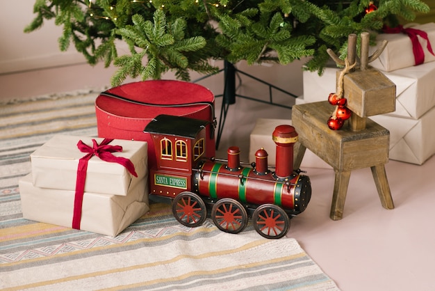 Photo santa claus christmas express toy and wooden old deer toy and gifts under christmas tree