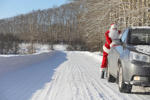 Дед Мороз приходит с подарками извне. Санта в красном костюме с бородой и в очках идет по дороге к Рождеству. Дед Мороз приносит детям подарки.