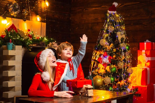 Santa claus coming. Mother and little child boy adorable friendly family having fun. Family having fun at home christmas tree. Mom and kid play together christmas eve. Happy family. Family holiday