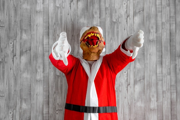 Santa claus costume has naughty expression and showing thumbs down, expressing disapproval, negative feedback. Indoor studio shot isolated on gray background.