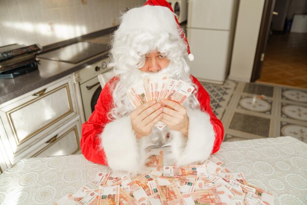 Santa claus counts money at home in the kitchen