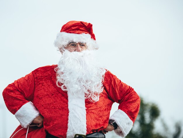 Santa Claus die zich met wapens bevindt die op zijn heupen rusten die zijn rode zak grijpen. kersttijd