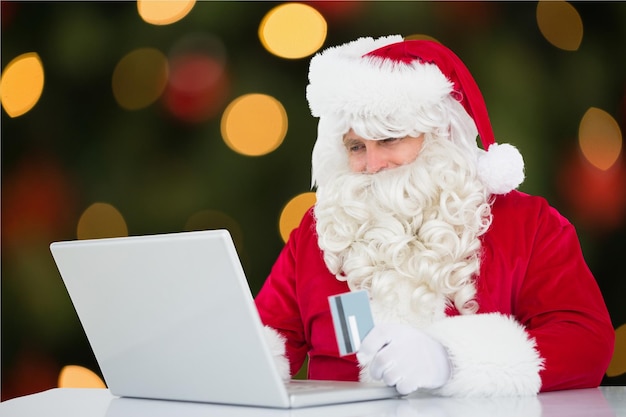 Santa claus doing online shopping with credit card on laptop