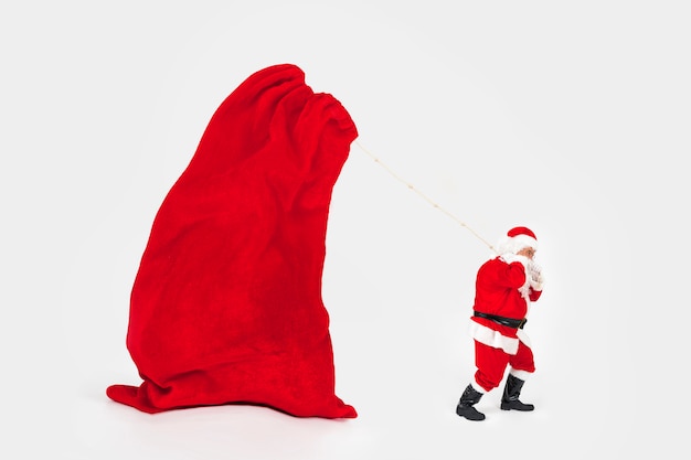 Foto babbo natale trascinando la borsa del nuovo anno gigante