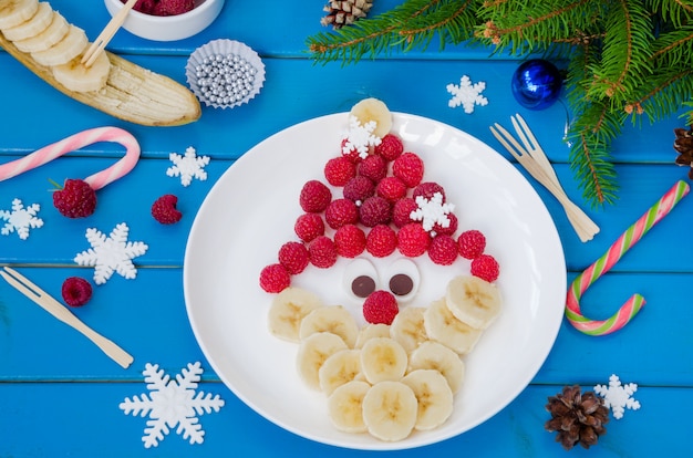 ラズベリーとバナナのチョコレートで作られたサンタクロースの顔。クリスマスと新年の面白い食べ物のアイデア