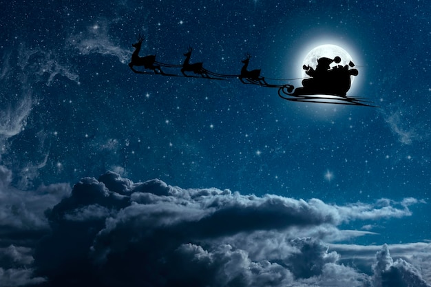 Photo santa claus flies on christmas eve in the night sky with snow