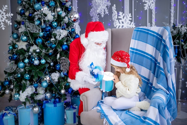 Santa Claus gives a baby girl a gift at the Christmas tree