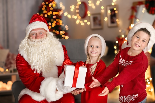 美しいクリスマスの装飾が施された部屋で子供たちにプレゼントを贈るサンタクロース