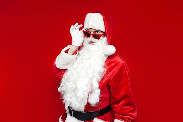 Santa claus in glasses looks at the camera and suspects on colored background puzzled man