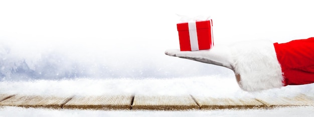 Santa Claus hand holding a wrapped Christmas present.