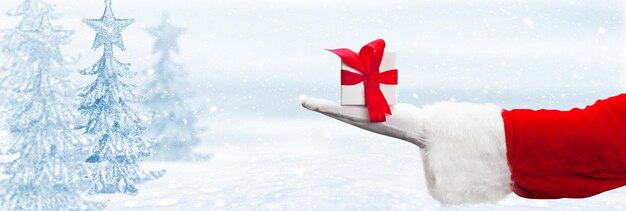 Santa Claus hand holding a wrapped Christmas present.