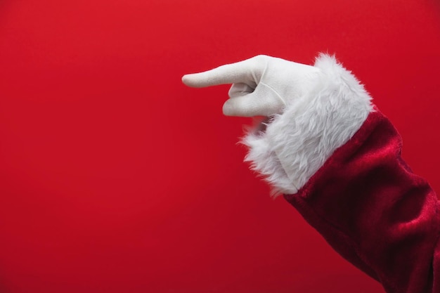 Santa Claus hand pointing finger against a red background