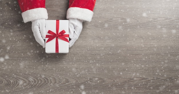 Foto le mani del babbo natale sta tenendo un contenitore di regalo bianco con il nastro rosso