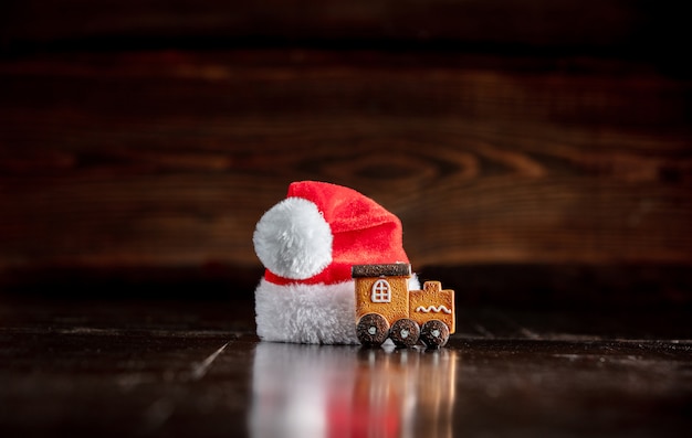 Santa Claus hat and gingerbread cookie on wooden table