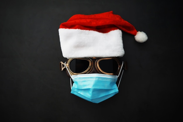 Santa Claus hat, glasses and nose with face mask on red background. Christmas or New Year celebration concept. Christmas reindeer made from protective face mask and decorations. Health care concept.