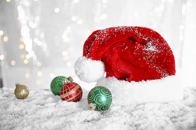 Santa Claus hat with baubles on a snowy table