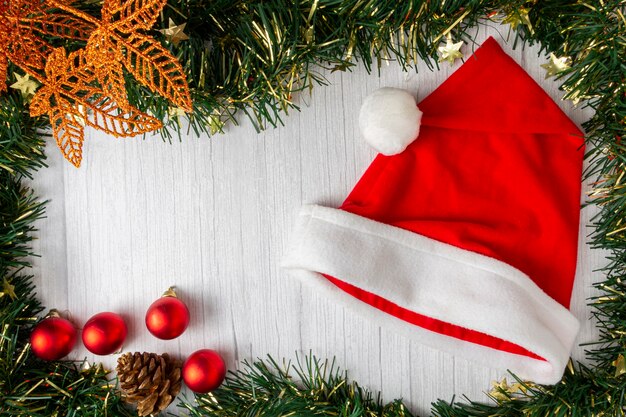 Santa Claus hat with Christmas decorations on wooden table.