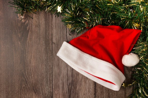 Santa Claus hat with Christmas decorations on wooden table.