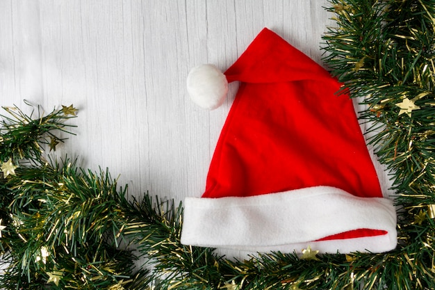 Santa Claus hat with Christmas decorations on wooden table.