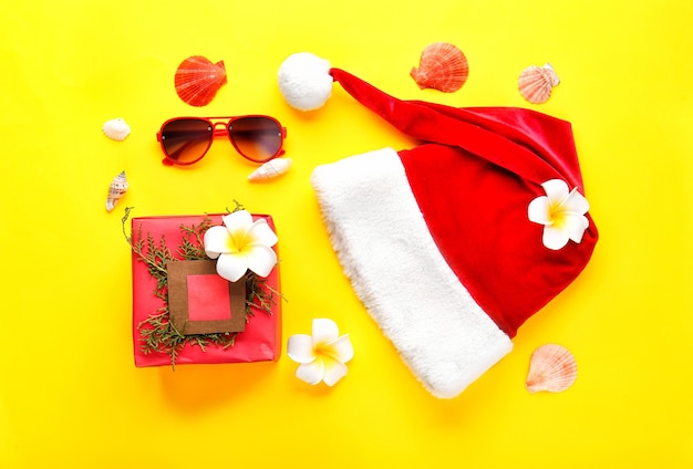 Santa claus hat with christmas gift and sunglasses on color