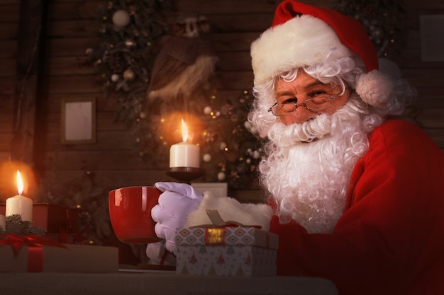 Santa Claus having a rest in a comfortable chair near the fireplace at home.