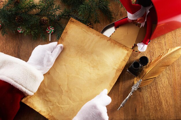 Фото Санта-клаус с пустым списком желаний в руках на деревянном столе