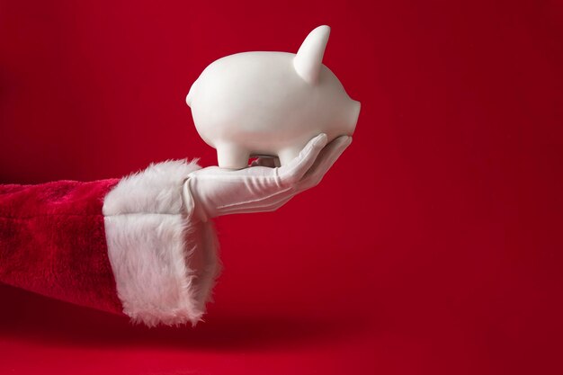 Santa claus holding a christmas piggy bank money box festive saving concept