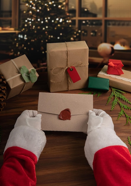 Санта-клаус держит элегантный конверт на расфокусированном уютном домашнем фоне