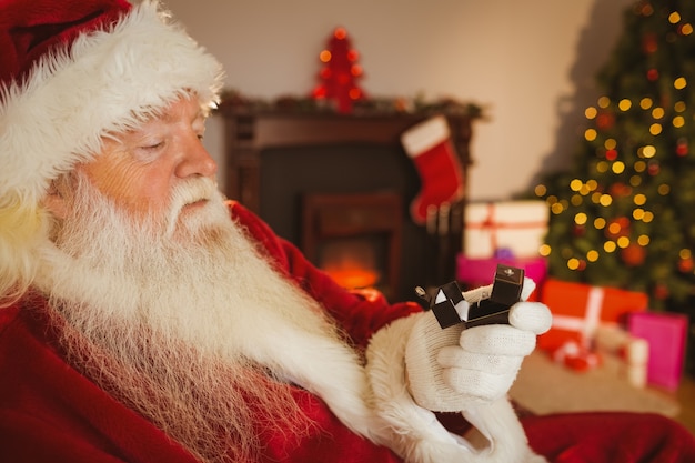 Santa claus holding engagement ring with his box