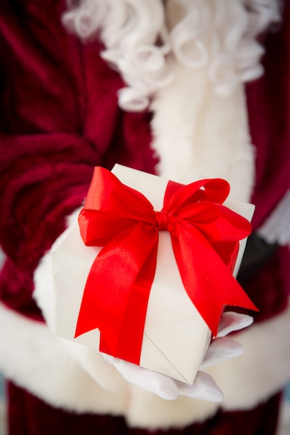 Santa Claus holding gift box in hands. Christmas holiday concept